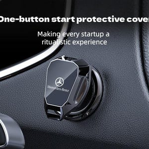May include: A black, angular, flip-up protective cover for a car engine start button, featuring the Mercedes-Benz logo and text. The text on the image reads: One-button start protective cover. Making every startup a ritualistic experience.