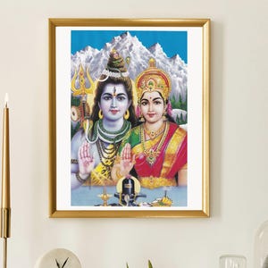 May include: A framed print featuring Hindu deities, Shiva and Parvati, against a backdrop of snow-capped mountains and a blue sky. The artwork is in a gold frame and is displayed on a white mantelpiece with decorative items.
