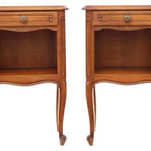 Può includere: Due comodini in legno coordinati con finitura marrone caldo. Ognuno ha un piccolo cassetto con pomello decorativo, un ripiano aperto e gambe curve. I comodini sono progettati in stile classico.