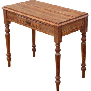 May include: A rectangular wooden desk with a single drawer and ornate legs. The desk is made of light brown wood with visible grain and a decorative drawer pull. The legs are turned and feature a bulbous design.