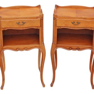 May include: A pair of antique wooden nightstands. Each nightstand has a drawer with a decorative handle, an open shelf, and curved legs. The wood has a warm, medium brown tone, and the design is classic and elegant.