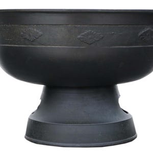 May include: A black, pedestal-style bowl with a wide rim and a decorative band featuring leaf-like designs. The bowl is supported by a sturdy base, creating an elegant and functional piece for serving or display.