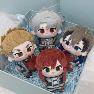 May include: Four plush dolls with embroidered facial features and stylised hair in blonde, silver, brown, and reddish-brown. Each doll wears a grey and white patterned outfit with detailed stitching, arranged together in a light blue gift box.