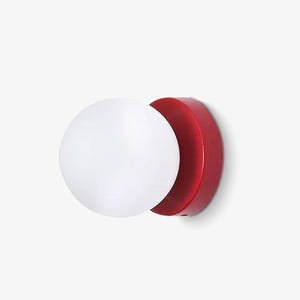 May include: A contemporary wall light with a white globe-shaped lampshade and a circular, red mounting plate. The design is minimalist and geometric, suitable for various interior styles. The light fixture is mounted on a white wall.