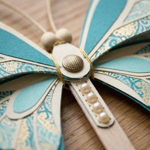 Close up of brad fastener and pull tab mechanism on paper butterfly craft showing flapping wing detail