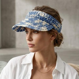 Könnte beinhalten: Blau-weißer gehäkelter Visor mit Krempe. Der Visor wird auf dem Kopf getragen und besteht aus einem gewebten Material. Der Visor ist ein modisches Accessoire zum Sonnenschutz.