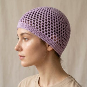 Peut inclure: Un bonnet en crochet lavande avec un motif ajouré. Le chapeau est fait d'un fil doux et a un bord côtelé. Le chapeau est porté par une personne.