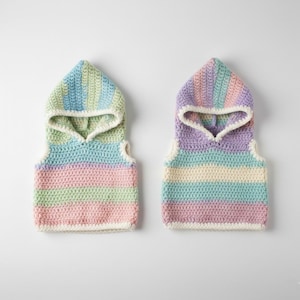 May include: Two pastel-colored crochet hooded vests. One vest features stripes of pink, green, and blue, while the other has purple, blue, and cream stripes. Both vests have a white trim and are displayed on a white background.