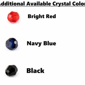 May include: A chart titled Additional Available Crystal Colors displaying three faceted beads. The first is bright red, the second is navy blue, and the third is black. Each bead is labeled with its corresponding color name in bold black text.
