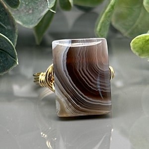 May include: A set of three ceramic mugs with a speckled, matte finish in cream, light grey, and dark grey. Each mug has a simple, minimalist design, suitable for coffee or tea.