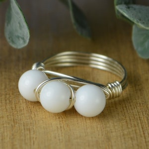 May include: A silver wire wrapped ring with three white beads.
