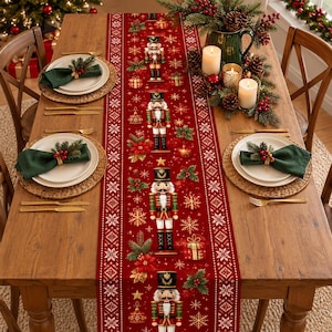 May include: A red fabric table runner featuring a repeating pattern of nutcrackers, poinsettias, snowflakes, and gift boxes. The runner is centred on a wooden dining table set with white plates, dark green napkins, and gold cutlery.