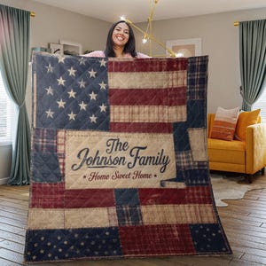 Könnte beinhalten: Eine Steppdecke mit einem Patchwork-Design der amerikanischen Flagge. Die Decke verwendet marineblaue, rote und beige Stoffe. Das Mittelteil zeigt den Text "The Johnson Family Home Sweet Home" in einer Schriftart.