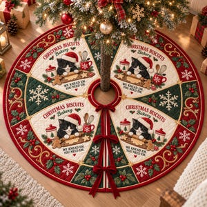 May include: A round, quilted Christmas tree skirt featuring a red and green pattern with white snowflakes and holly. Four panels display a black and white cat wearing a Santa hat, baking with the text "CHRISTMAS BISCUITS Bakery WE KNEAD EM. YOU NEED EM."