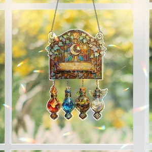 May include: A stained glass window hanging with a decorative frame, a crescent moon, and four hanging potion bottles. The bottles are filled with red, blue, green, and clear liquids. The window is hanging in front of a window with a blurred green background.