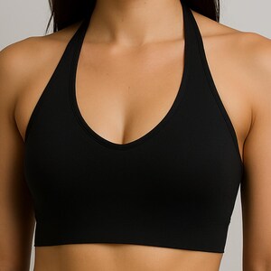 May include: A black halter top with a deep V-neck. The top is made of a smooth, solid fabric and has a classic, minimalist design. The halter straps extend up to the neck, creating a sleek and modern look. Suitable for various activities.