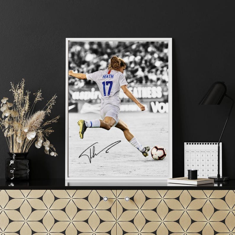 May include: Black and white framed print of a soccer player in action, kicking a soccer ball. The player wears a white jersey with the number 17 and the name "Heath". The print includes an autograph.