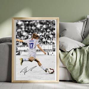 May include: Framed photograph of a soccer player in action, kicking a soccer ball. The player wears a white jersey with the number 17 and the name "Heath". The image is in black and white, with the player in color. A signature is visible.