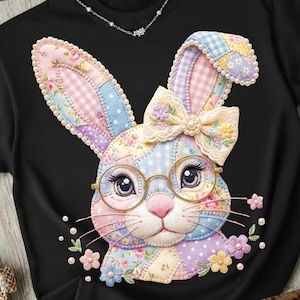 Pode incluir: Camiseta preta com um design de rosto de coelho de retalhos. O coelho usa óculos redondos e um laço, com padrões florais e xadrez nas orelhas. O design incorpora detalhes florais e pérolas, criando uma aparência caprichosa e decorativa.
