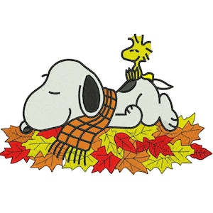 May include: An embroidery design featuring a white beagle with a black ear and a black spot on its back, wearing an orange and brown plaid scarf. A small yellow bird sits on the beagle's back, both resting on a pile of red, orange, and yellow leaves.