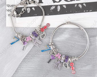 May include: Two silver-toned charm bracelets featuring various dangling elements including a blue number seven, a purple heart, a pink butterfly, a crystal-encrusted logo, and red circular charms. The bracelets have a flexible metal chain design.