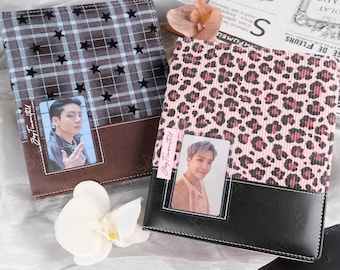 May include: Two square photo albums with clear display windows on the front covers. One album features a brown plaid pattern with black stars and a brown base. The other has a pink and black leopard print with a black base. Both include photo cards.