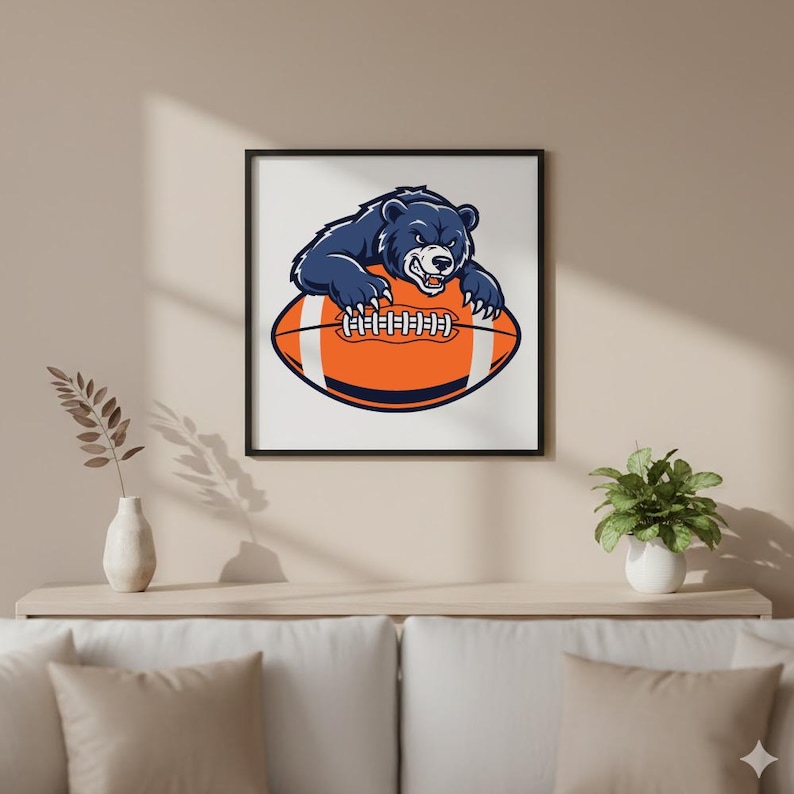 May include: A framed print featuring a navy blue bear with a fierce expression, perched atop an orange and white football. The artwork is set against a white background, framed in black, and suitable for sports enthusiasts.