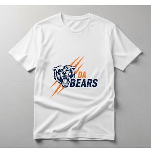 May include: White t-shirt featuring a navy blue bear graphic with the text "DA BEARS" in navy blue and white. The design includes orange claw marks. A classic crew neck tee.