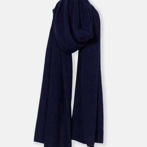 May include: A navy blue scarf, draped and folded, against a white background. The scarf appears to be made of a soft material, with a slight sheen. The scarf is a solid color, with no visible patterns or embellishments.