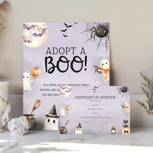Könnte beinhalten: Ein hellviolettes Halloween-Schild und ein passendes Adoptionszertifikat mit Aquarellillustrationen von Geistern, einer Spinne, Fledermäusen, einem Mond und einem Kürbis. Das Schild trägt die Aufschrift ADOPT A BOO! und enthält Zeilen für Namen.