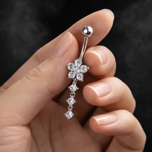 Piercing de umbigo delicado com flor, em aço cirúrgico, com corrente pendente de cristal de zircônia cúbica.