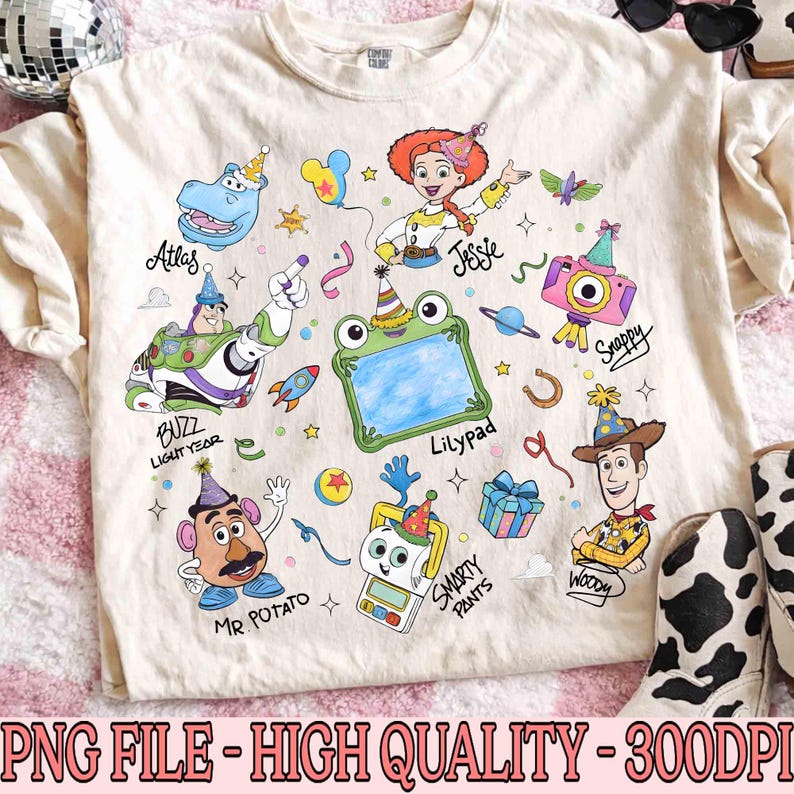 May include: Cream-colored t-shirt featuring colorful cartoon characters including Buzz Lightyear, Jessie, and Woody. The shirt has the text "Atlas", "Jessie", "Buzz Lightyear", "Lilypad", "Mr. Potato", "Snappy", "Smarty Pants", and "Woody".