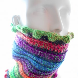 May include: A colourful crocheted neck warmer with a scalloped edge. The neck warmer is made with a variety of colours, including green, purple, blue, orange, and pink.