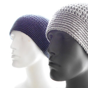 Puede incluir: Dos gorros de punto, uno gris y otro azul oscuro, se muestran en maniquíes. El gorro gris tiene un patrón de punto simple y el gorro azul oscuro tiene un patrón de punto más texturizado.