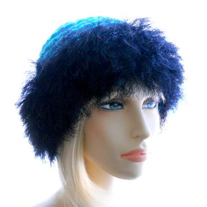 May include: A blue and black crocheted hat with a fluffy brim. The hat is worn by a mannequin with blonde hair.