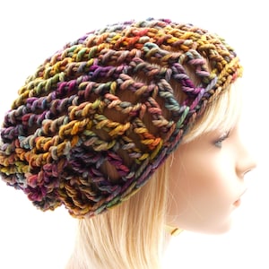 Puede incluir: Un gorro de punto de ganchillo en un hilo multicolor con tonos de marrón, morado, naranja y verde.