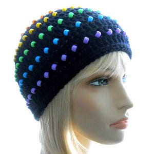 May include: A black crocheted beanie with colorful beads. The beads are arranged in a rainbow pattern.