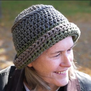 May include: A crocheted hat in grey, green, and brown hues. The hat has a brim and a textured stitch design. This cosy hat is ideal for cooler weather, adding a handmade touch to any outfit. The hat is a great accessory.