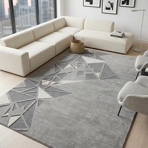 May include: A large rectangular area rug featuring a gray base with a raised geometric pattern of triangles and lines in shades of charcoal, light gray, and off-white. The rug has a textured pile and covers a significant portion of the floor.