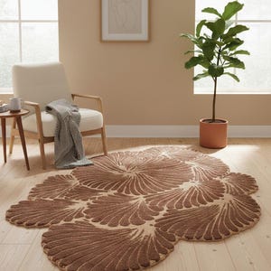 May include: A brown area rug with a floral design, placed on a wooden floor. The rug has a unique shape and a textured appearance. The room also features a beige armchair, a small side table, and a potted plant.