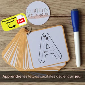 Könnte beinhalten: Ein Set Lernkarten mit dem Buchstaben "A", einem blauen und weißen Marker. Die Karten sind mit einem Metallring verbunden. Ein gelbes PDF-Download-Symbol und ein rundes Logo mit dem Text "CURIEUX et joyeux" sind ebenfalls zu sehen.