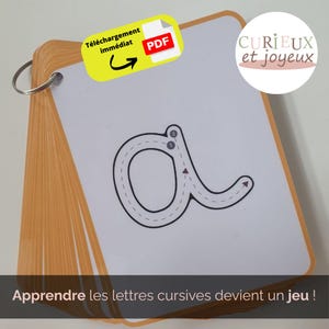 Peut inclure: Une carte d'apprentissage reliée en spirale avec la lettre cursive "a" et des guides de traçage numérotés. La carte fait partie d'un ensemble, avec le texte "Apprendre les lettres cursives devient un jeu!" en bas. Un autocollant jaune indique un téléchargement PDF.