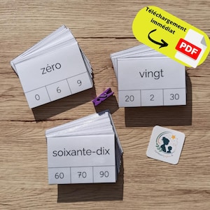Peut inclure: Trois piles de cartes pédagogiques rectangulaires blanches avec du texte noir. Les cartes du dessus affichent les mots zéro, vingt et soixante-dix, avec des chiffres correspondants en dessous. Une petite pince à linge violette et un autocollant carré.