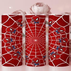 Może przedstawiać: Zestaw trzech czerwonych kubk&oacute;w z białym wzorem pajęczyny i grafiką Spider-Mana z kresk&oacute;wek. Kubki mają cylindryczny kształt i są ozdobione emblematem superbohatera.