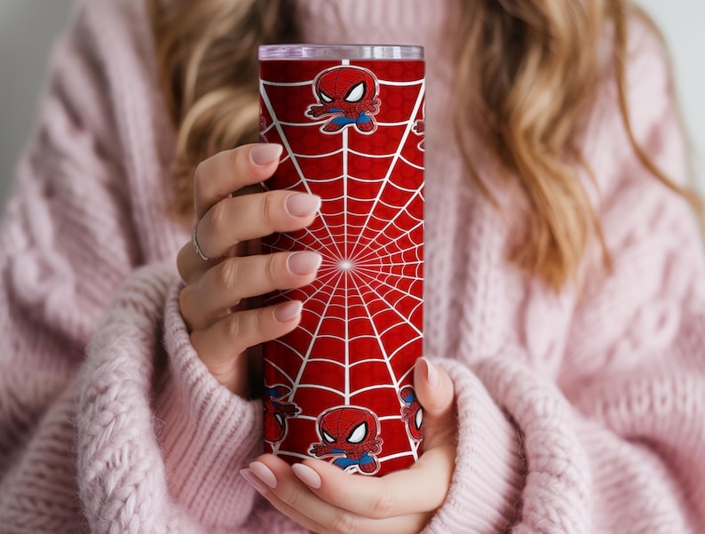 Może przedstawiać: Czerwony kubek z białym wzorem pajęczyny i ilustracjami Spider-Mana. Cylindryczny kubek jest prawdopodobnie ze stali nierdzewnej. Wz&oacute;r powtarza się wok&oacute;ł całego kubka.
