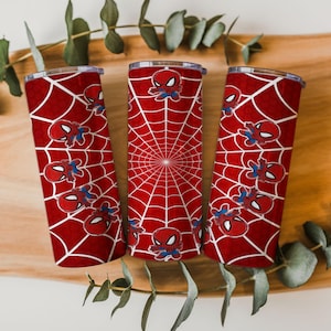Może przedstawiać: Trzy czerwone kubki termiczne z motywem Spider-Mana. Każdy kubek ma biały wz&oacute;r pajęczyny i wiele ilustracji postaci Spider-Mana. Kubki są cylindryczne i mają srebrną obręcz i pokrywkę.