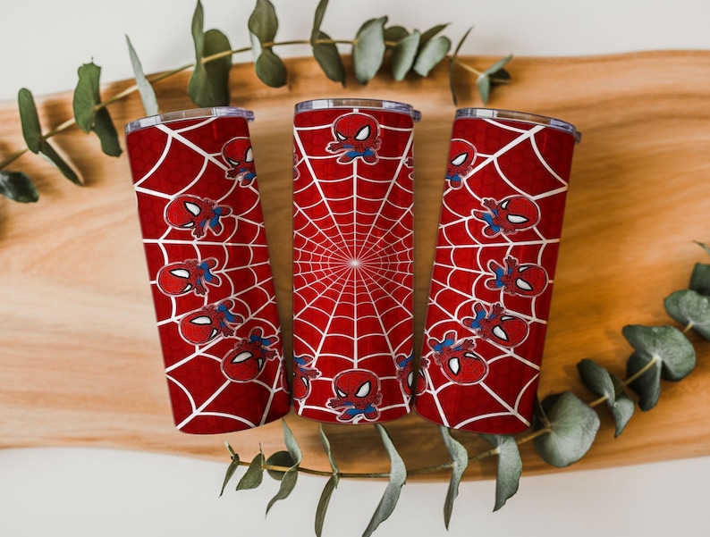 Może przedstawiać: Trzy czerwone kubki termiczne z motywem Spider-Mana. Każdy kubek ma biały wz&oacute;r pajęczyny i wiele ilustracji postaci Spider-Mana. Kubki są cylindryczne i mają srebrną obręcz i pokrywkę.