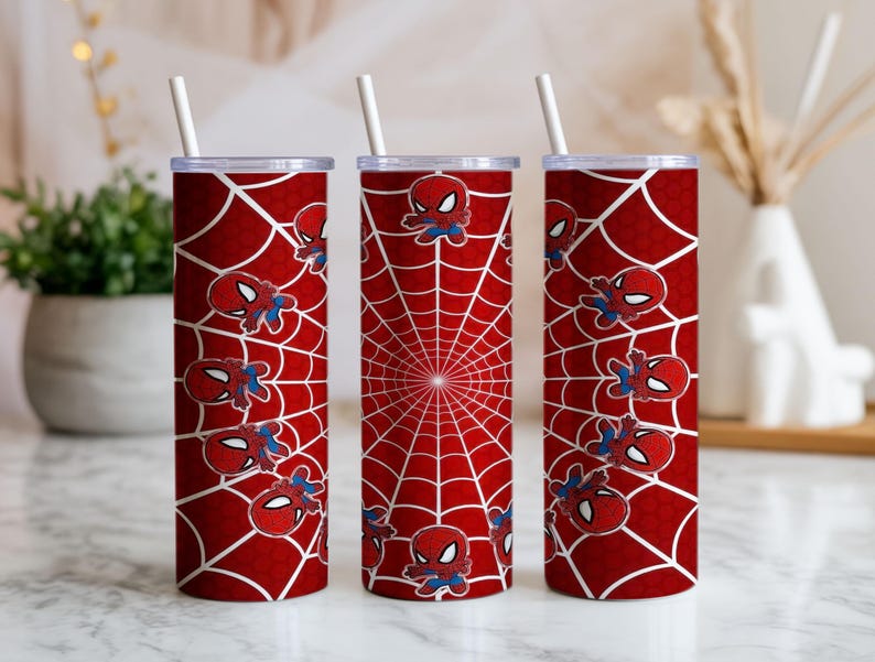 Może przedstawiać: Trzy czerwone kubki termiczne z białymi pajęczynami i grafiką Spider-Mana. Każdy kubek ma białą słomkę. Projekt przedstawia powtarzający się wz&oacute;r superbohatera i centralny wz&oacute;r pajęczyny.