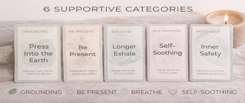 May include: Six supportive category cards with text including "Grounding", "Be Present", "Breathe", "Self-Soothing", and "Movement". Each card has a unique design and message. A lit candle sits to the right of the cards.