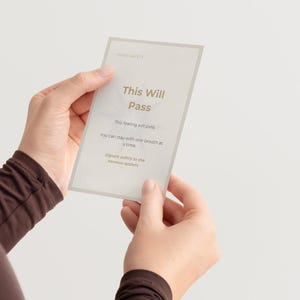 May include: A rectangular card with the text "This Will Pass" in a soft, neutral font. The card also includes the phrases "This feeling will pass," "You can stay with one breath at a time," and "Signals safety to the nervous system."